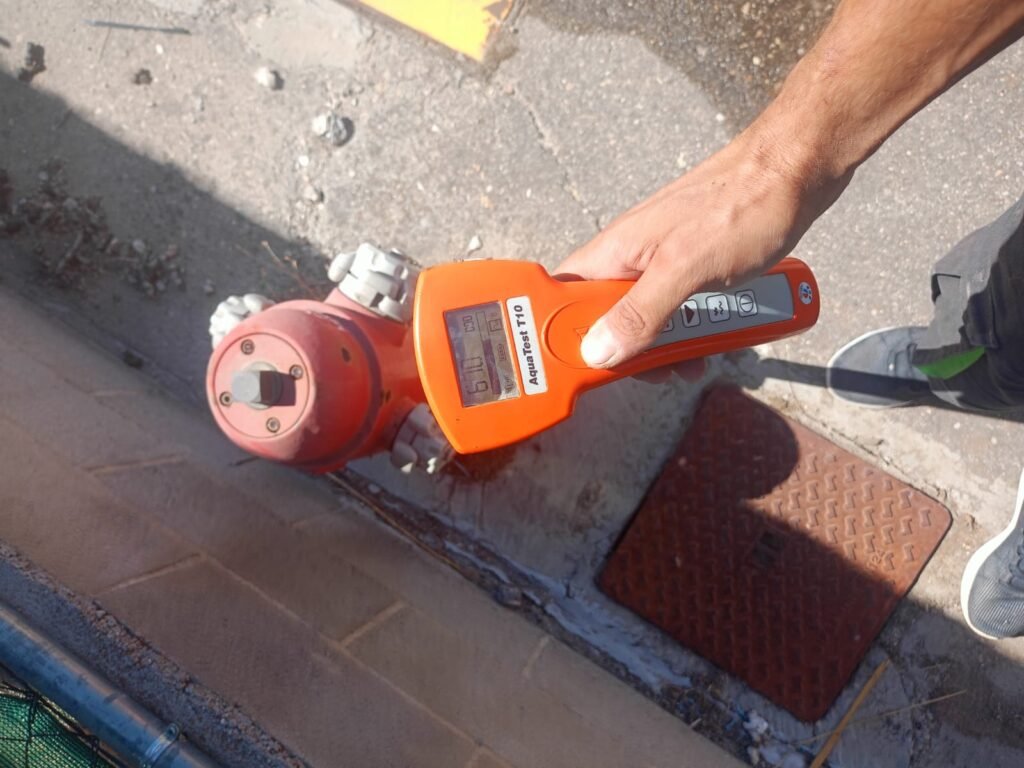 En la imagen se ve un operario de todofugaslocalizaciones utilizando gas trazador para encontrar una fuga en un hidrante antiincencios